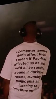 a man with headphones on his ears standing in front of a screen that says computer games don't effect kids, i mean if pac - man