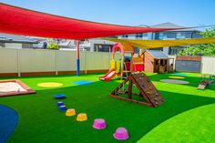 an outdoor play area with artificial grass and colorful playground equipment