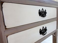 an old white dresser with black handles and knobs