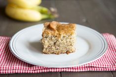 a piece of cake sitting on top of a white plate next to some ripe bananas