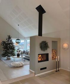 a living room filled with furniture and a fire place next to a christmas tree in the corner