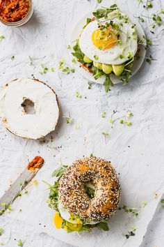 two bagels with an egg on top and another bagel topped with sprouts