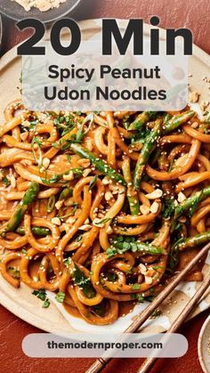 a plate full of noodles and vegetables with chopsticks next to it on a table