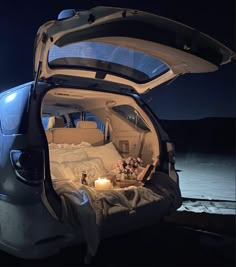 an open trunk of a car with candles and flowers on the bed in it at night