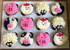 twelve cupcakes decorated with farm animals and sheep's faces are in a box