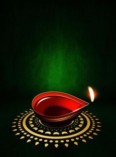 a red bowl sitting on top of a table next to a lit candle