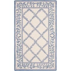 a white rug with blue trimmings and leaves on the bottom, in front of a