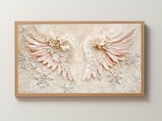 two pink angel wings with snowflakes on them are mounted in a wooden frame