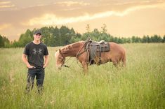 a man standing next to a horse in a field