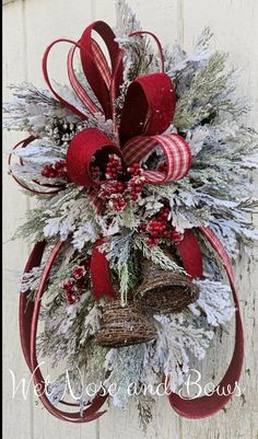 a christmas wreath hanging on the side of a white wooden wall with red and silver decorations