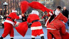 two men dressed as santa claus dancing in the street