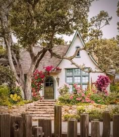 a white house with pink flowers on the front and stairs leading up to it's entrance