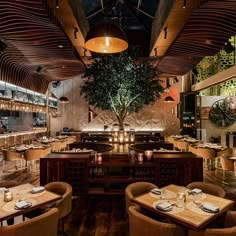 an empty restaurant with wooden tables and chairs in front of a large tree on the wall