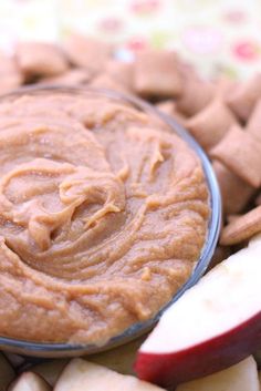 an apple and peanut butter dip in a glass bowl next to some cut up apples