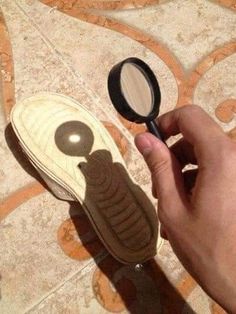 a hand holding a magnifying glass next to a pair of shoe soles