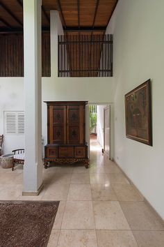 an empty room with a large wooden cabinet in the center and paintings on the wall