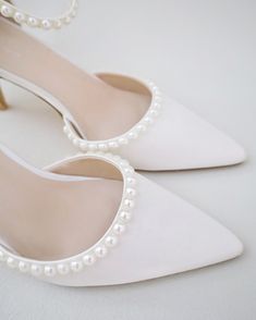 a pair of white high heels with pearls on the toe and heel are sitting next to each other