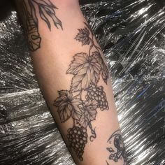 a woman's arm with grapes and leaves on it