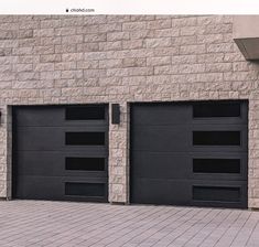 two black garage doors on the side of a brick building