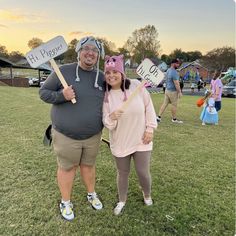 two people standing in the grass holding signs