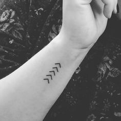 black and white photo of a person's arm with an arrow tattoo on it