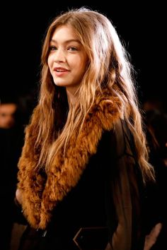 a woman with long hair wearing a fur stole around her neck and looking off to the side