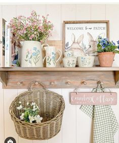 a shelf that has some flowers and mugs on it with a sign above it