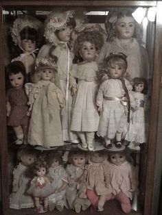 an old fashioned doll display case with many dolls in it