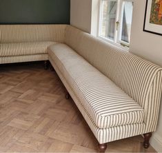 a striped couch sitting on top of a hard wood floor next to a window in a living room