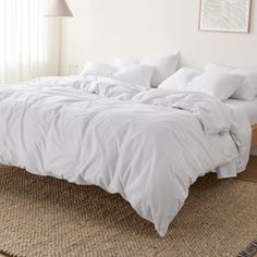 an unmade bed with white linens and pillows on top of it in a bedroom