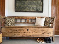 a wooden bench sitting in front of a wall with shoes on the floor next to it