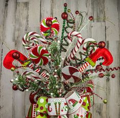 a christmas tree decorated with candy canes and ornaments on a wooden table next to a wall