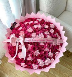 a large bouquet of pink and red roses in a round paper box with a ribbon tied around it