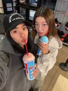 two young women are holding drinks and posing for the camera