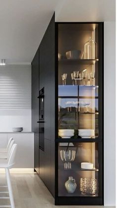 a modern kitchen with glass shelves and white chairs in front of the countertop area