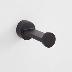 a black wall mounted toilet paper dispenser on a white wall with a circular handle