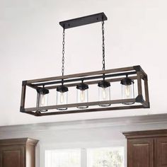 a light fixture hanging from the ceiling above a kitchen island with wooden cabinets and drawers