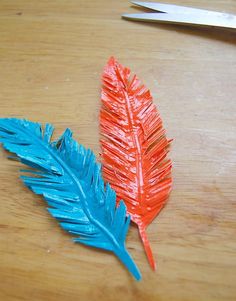 two red and blue feathers sitting on top of a wooden table