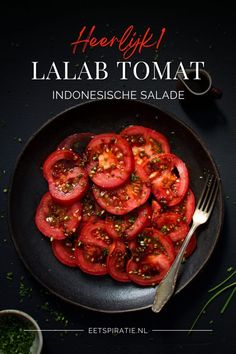 a black plate topped with sliced tomatoes on top of a table