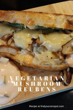 a close up of a sandwich on a cutting board with mushrooms and sauce in the background