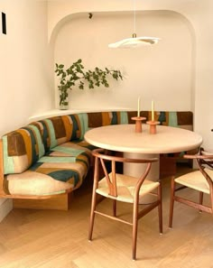 a corner table with two chairs and a couch in the middle is next to a potted plant