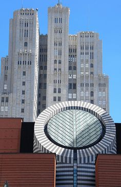 a large building with a circular window in front of it and tall buildings behind it