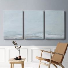 three paintings hanging on the wall next to a chair