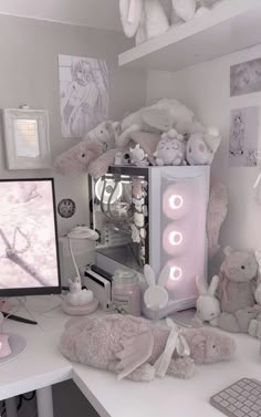 a white desk topped with a computer monitor and lots of stuffed animals on top of it