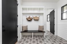 a black and white entryway with two coats hanging on the coat rack over the bench