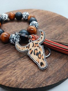 A combination of black, cow print, and dark wooden beads strung on doubled-up 5.5m stretch cord make up this western inspired keychain wristlet. A silver (alloy metal) split key ring and lobster clasp are attached, along with a "suede" cow head charm and multi-colored leather tassel. Western Key Rings, Casual Black Beaded Bracelets, Adjustable Black Beaded Bracelets For Everyday, Everyday Black Beaded Jewelry, Handmade Black Wristlet With Round Beads, Handmade Black Wristlet For Everyday Use, Black Handmade Wristlet For Everyday Use, Adjustable Black Casual Wristlet, Casual Black Adjustable Wristlet