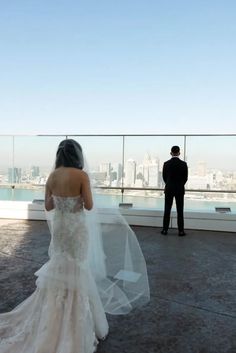 a bride and groom standing on top of a building looking out at the city skyline