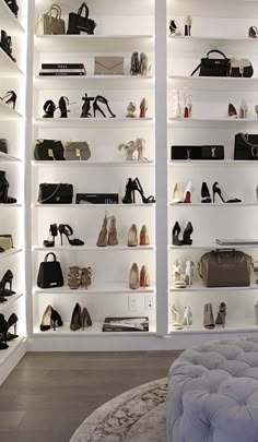 a room filled with lots of shoes and purses on shelves next to a round ottoman