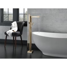 a white bath tub sitting next to a black chair in a bathroom with marble walls