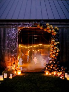 halloween decorations on display in front of a barn at night with candles and pumpkins